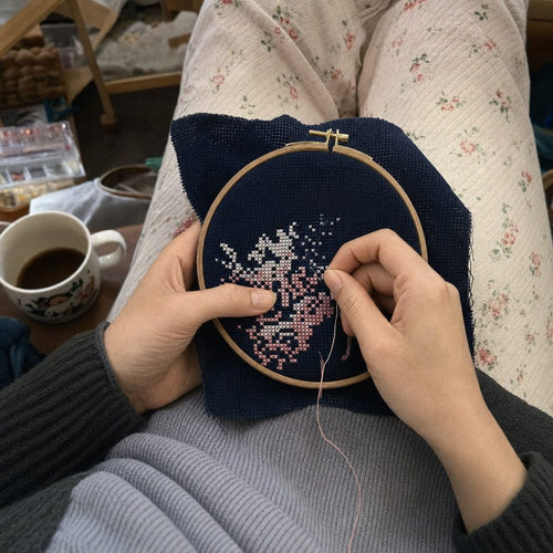 Cross-stitching on dark fabric with the GlimGlow Stitch Light lighting the hoop